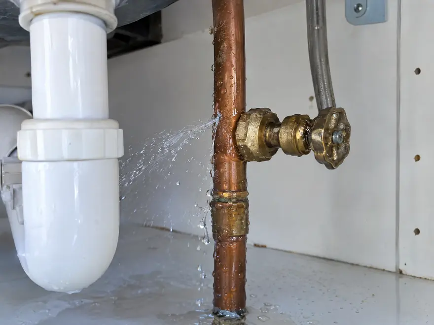 Water spraying from a leaking joint on a copper pipe