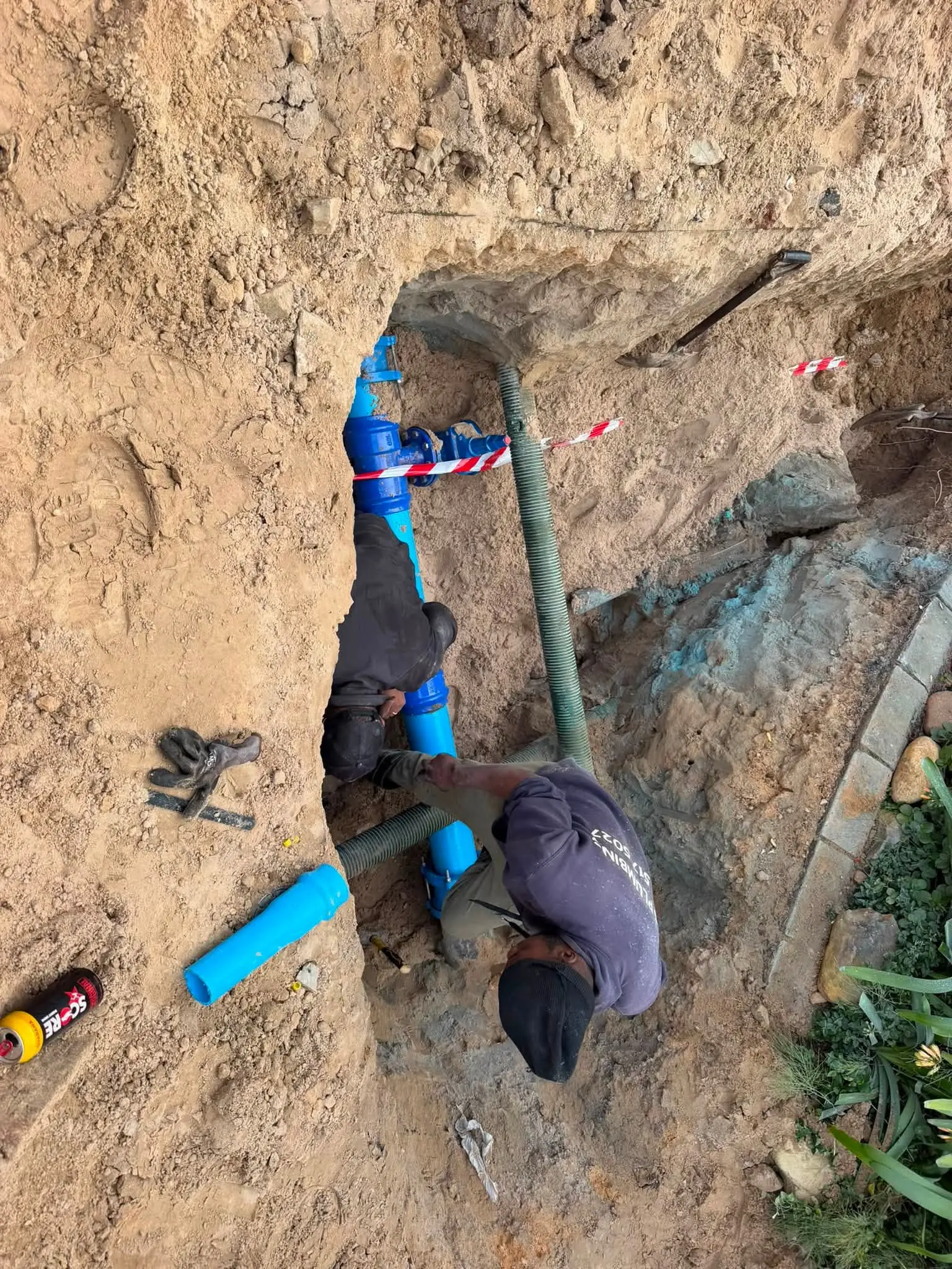 A JGS plumber in a trench, repairing an underground water line